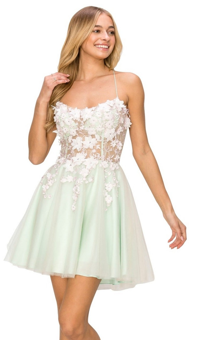 A woman wearing the Backless Sheer-Waist Floral Homecoming Dress 8053J, a sleeveless light green short dress with 3-D flowers on a sheer bodice, stands and smiles.